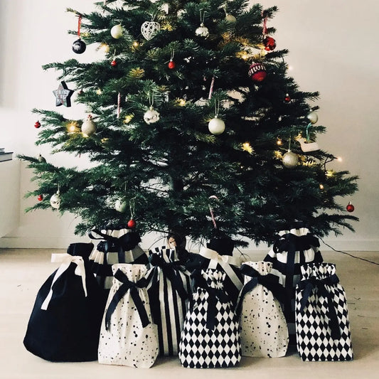 Stylish sustainable gift bags on display around a Christmas tree, eco-conscious gift wrapping
