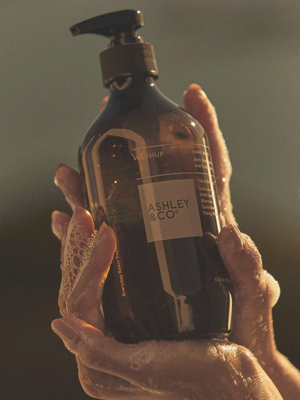 Ashley and Co Washup Hand Soap Parakeets Pearls bottle in a ladies hands with suds.