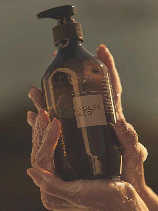 Ashley and Co Washup Hand Soap Parakeets Pearls bottle in a ladies hands with suds.