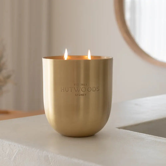 A lit gold Hutwoods XL candle displayed