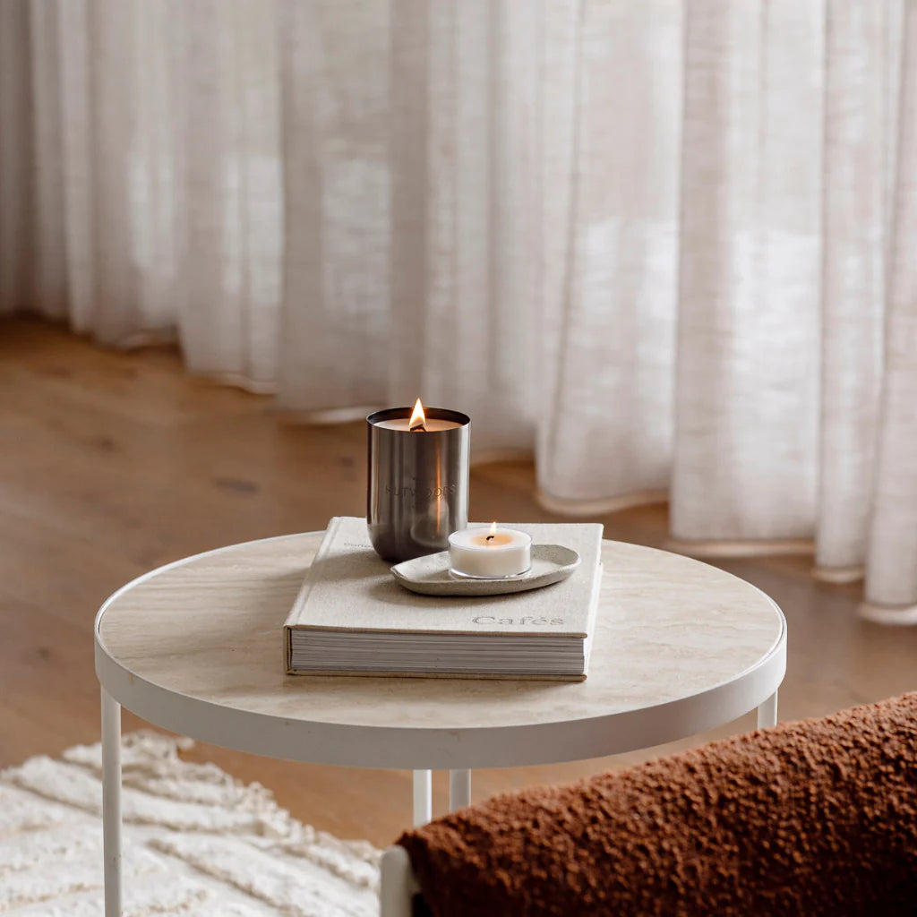 Lit black Hutwoods candle on marble side table