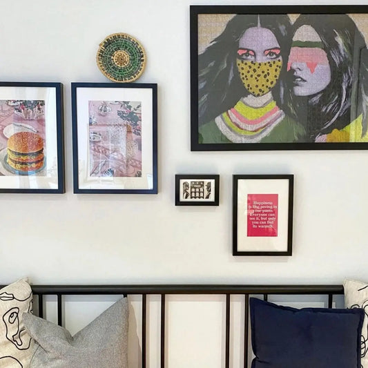 An eclectic art wall with framed pictures and a framed version of the Journey of Something Eden Edition puzzle on the wall. Gorgeous.