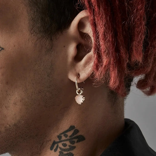 A close up of Stolen Girlfriends Club Rose Quartz Love Claw Anchor Earrings as worn by a man... yes, men can wear dangly earrings too.