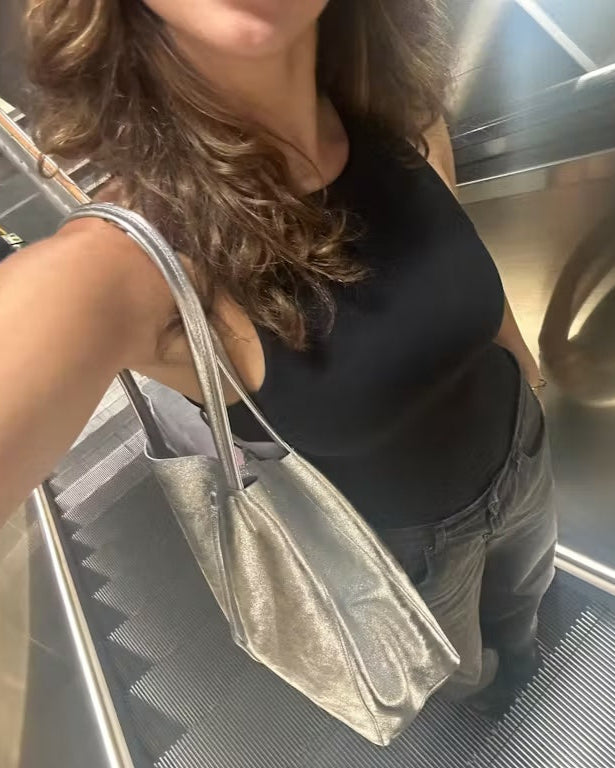 A Hunted customer sharing their love our Silver Metallic Leather Tote Bag... we love seeing our customer happy. A lady standing on an escalator with the silver tote bag over her shoulder.