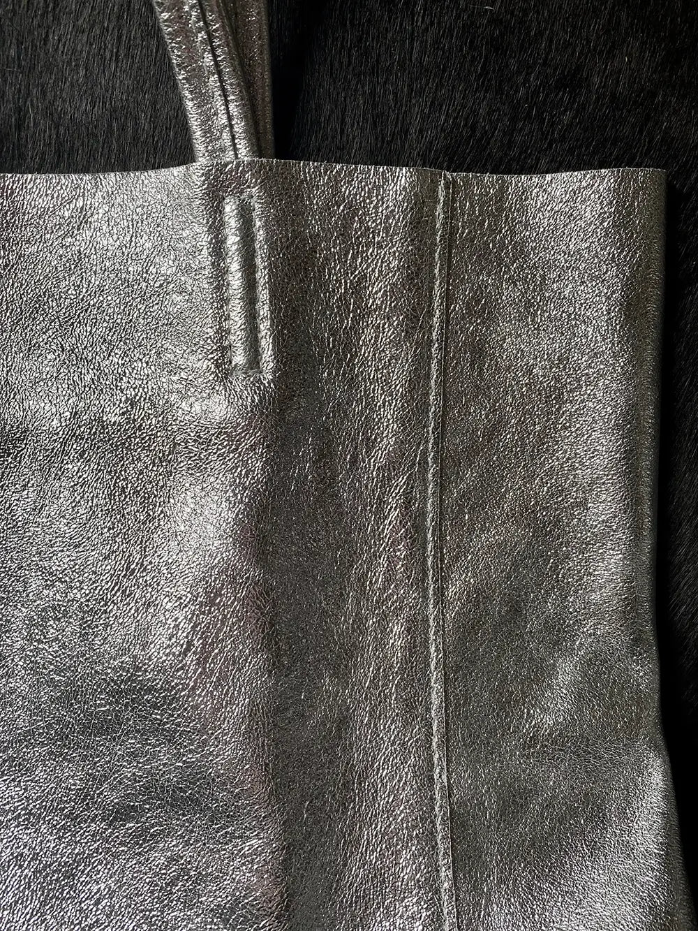 Close up detail of Silver metallic Maison Fanli large leather tote bag highlighting minimalist design and stitching.