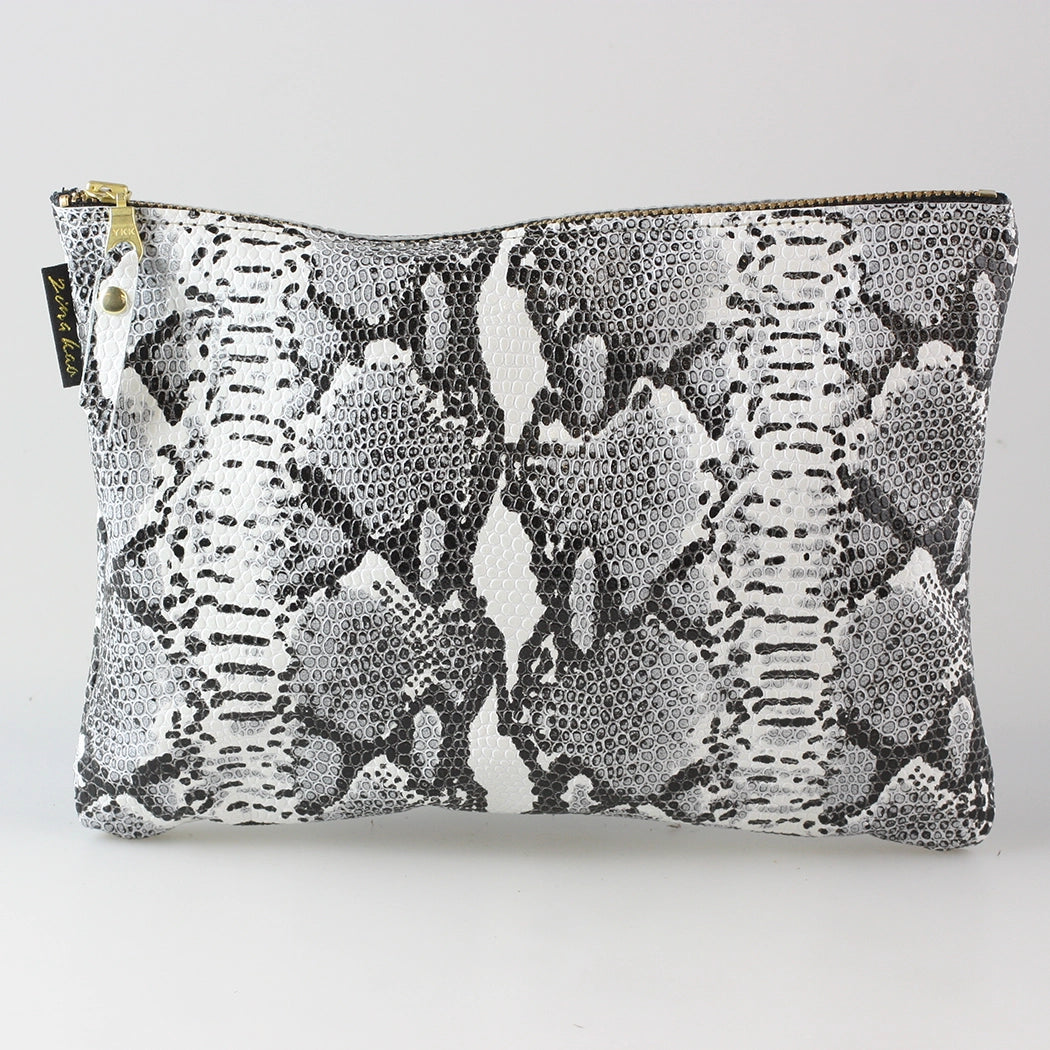 Snakeskin leather travel pouch filled and laying flat on a white background.