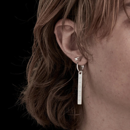 A close up of a model wearing Stolen Girlfriends Club's Silver I’ll Be Lightning Earring in a stack to give you a sense of scale. They're so stinking cute!