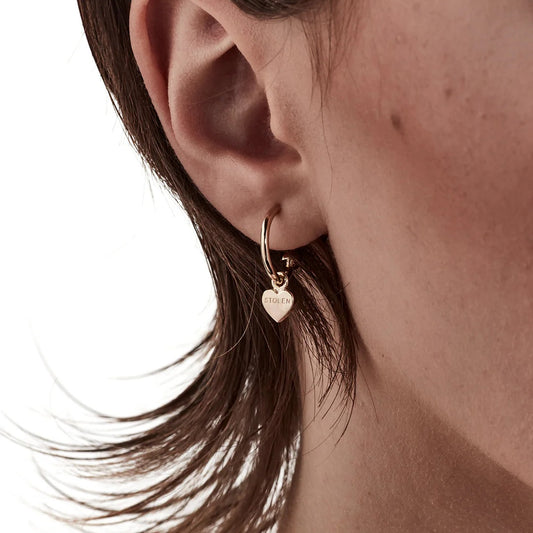 A close up of a models ear showcasing Stolen Girlfriends Club's Gold Stolen Heart Anchor Sleeper Earrings. Gorgeous.