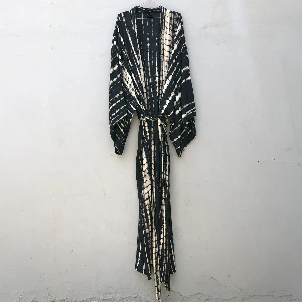 Hand-dyed black and white bamboo kimono robe with matching travel bag, hanging on a wall. Gorgeous!