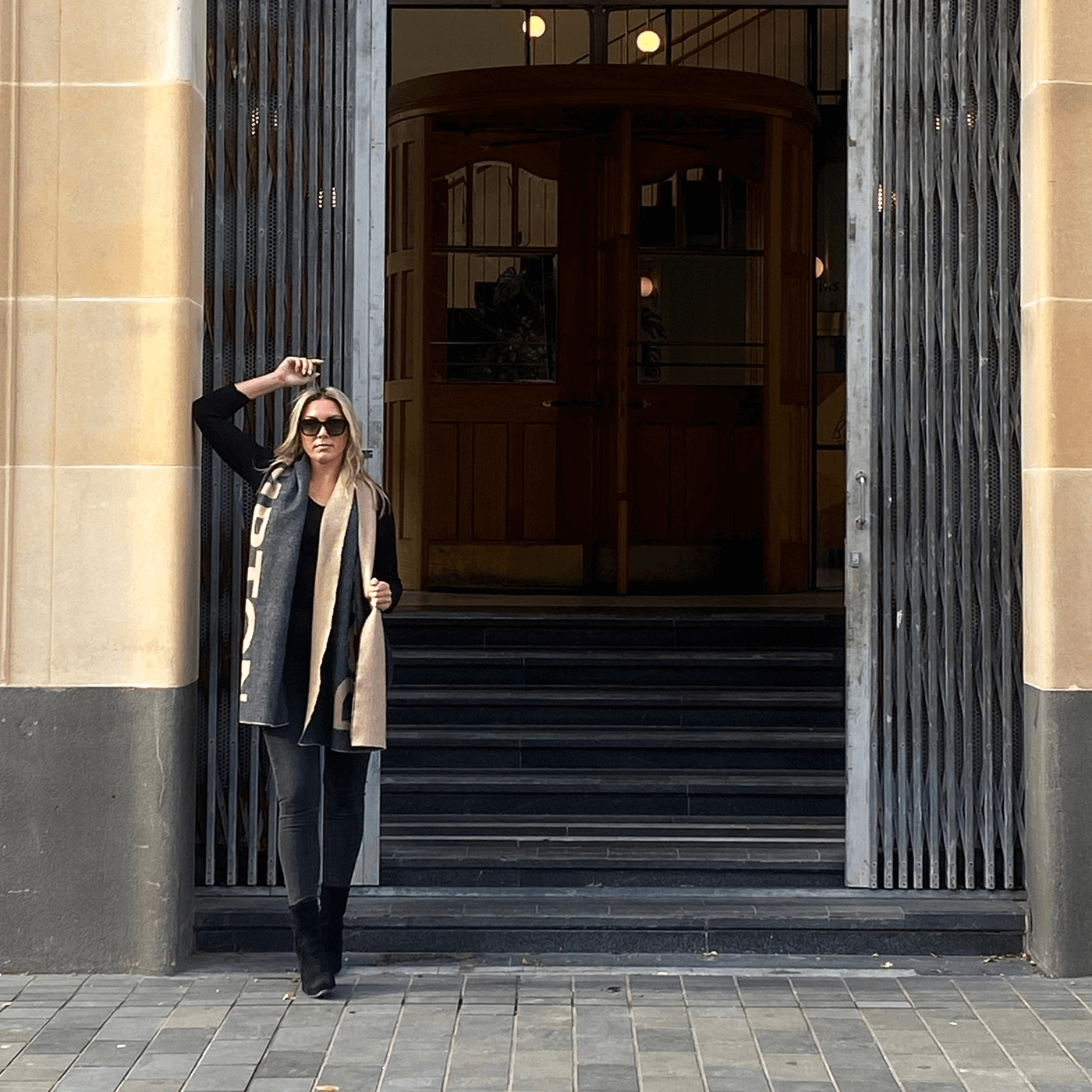 A model wearing the Ferguson Wool Logo Blanket Scarf with an all black outfit. Looks great!