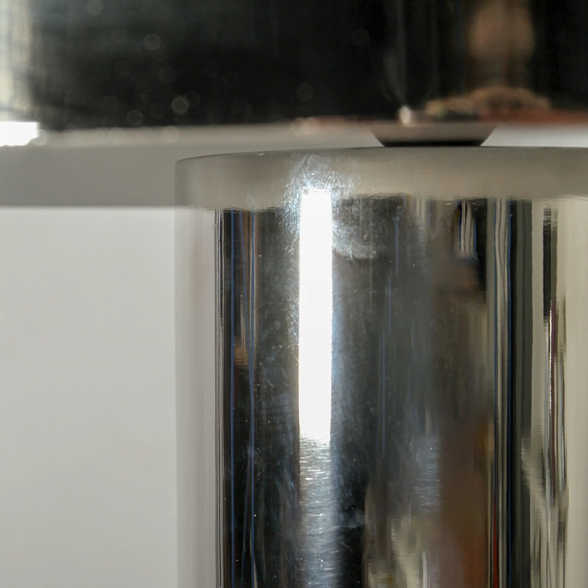 Close-up of where the Solstice lamp's shade meets its polished silver base.