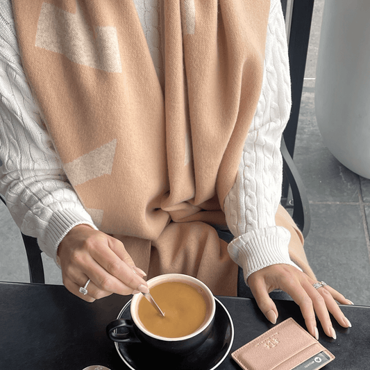 The Thompson Wool Scarf as worn on a model drinking coffee in a cafe. Timeless elegance.
