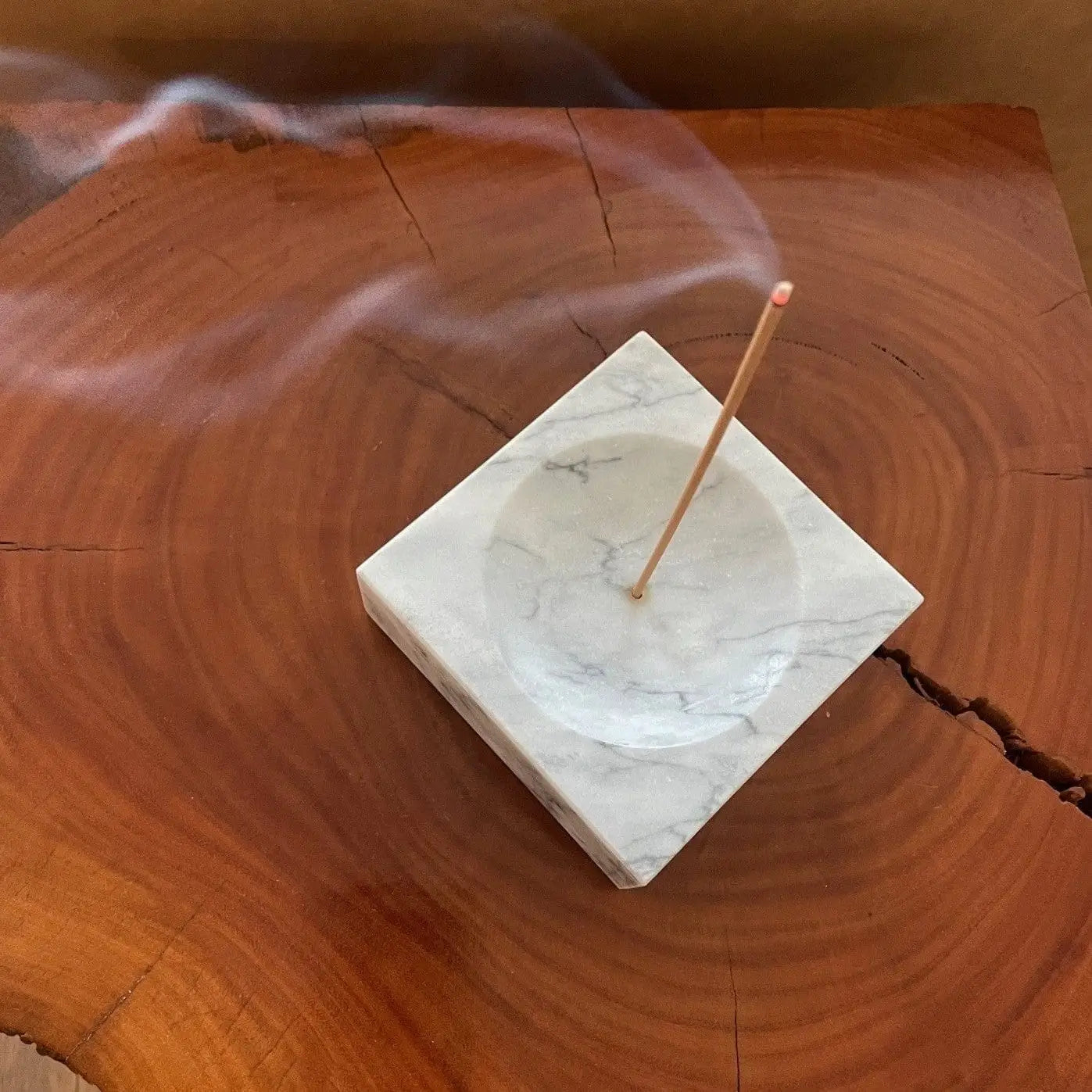 Incense stick burning in the Marble Incense Holder on a wooden tabletop.
