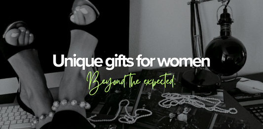 Monochrome flatlay of heeled shoes, pearl jewellery and vintage photographs on a desk, with text reading Unique gifts for women, beyond the expected