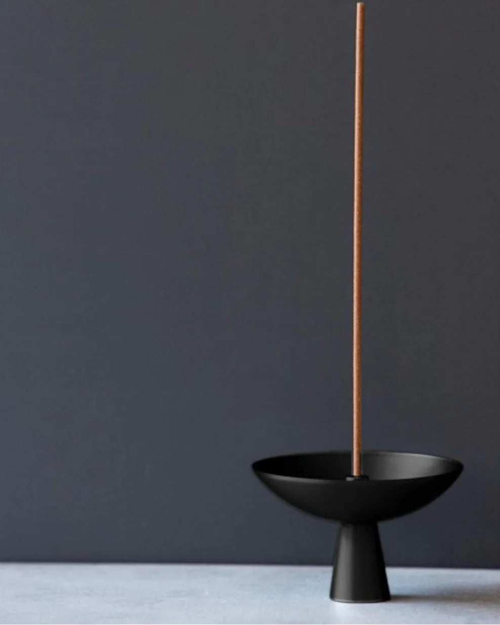 Side view of the Alta Saturn Nickel incense holder in a black finish with a burning incense stick, showcasing its contemporary sculptural design.