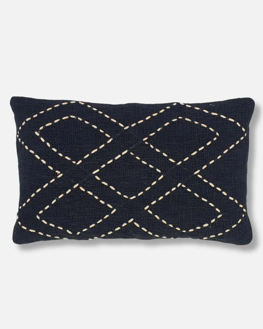 Black raw linen lumbar cushion with hand-stitched white diamond pattern on a light grey background.
