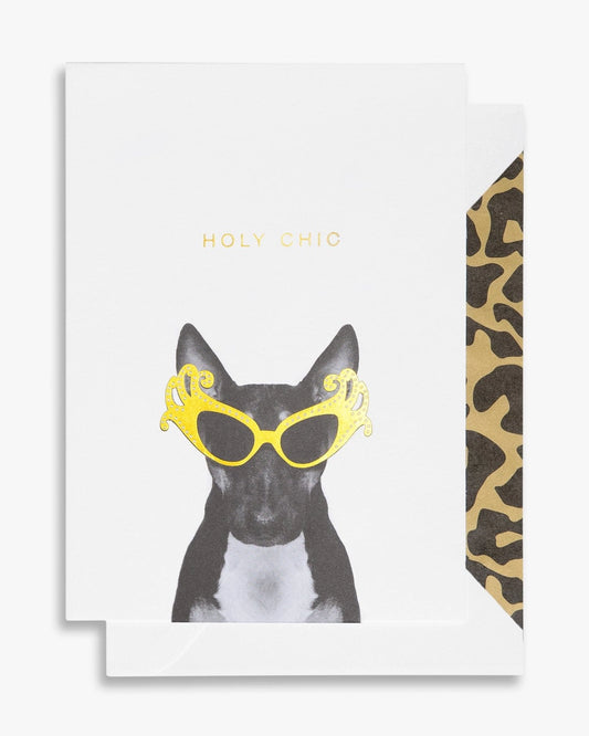 Greeting card with a white background featuring a stylised illustration of a dog wearing sunglasses and the text 'Holy Chic' in bold gold letters. The card has a blank interior and comes with a leopard print lined envelope.