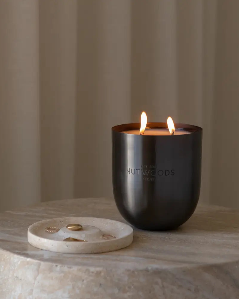 Gifts for the Hard-to-Buy-For: A large and luxurious black, double wicked Hutwood candle burning on a marble table