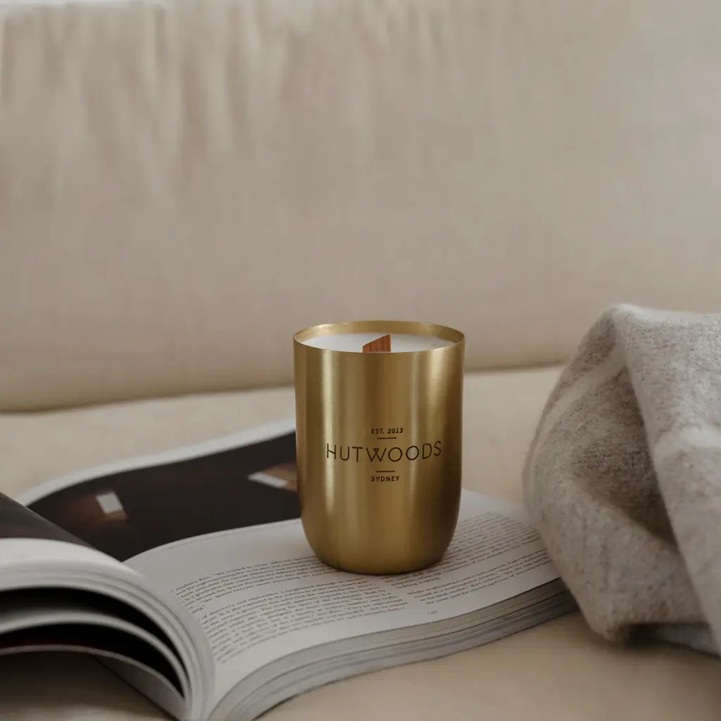 A brass/gold Hutwood candle positioned on a magazine. Super cosy. 