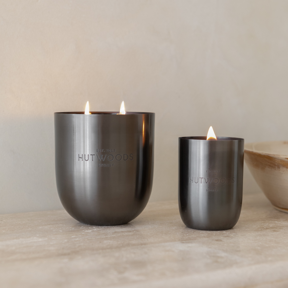 Two Hutwoods candles in black: the large 200+ hour candle with double wicks + the 80+ hour candle on a marble tabletop 