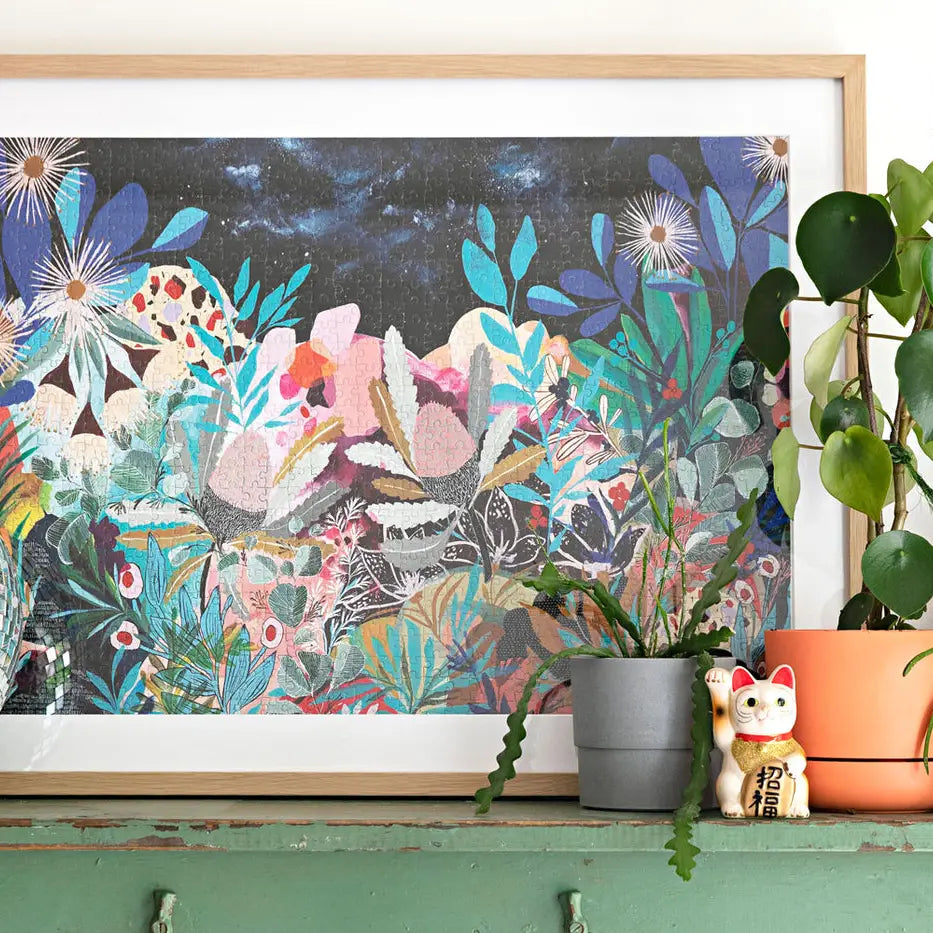 A framed 1000-piece Secret Garden puzzle of a  vibrant garden illustration by Georgia Pendlebury.