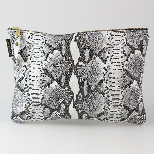 Snakeskin leather travel pouch filled and laying flat on a white background.