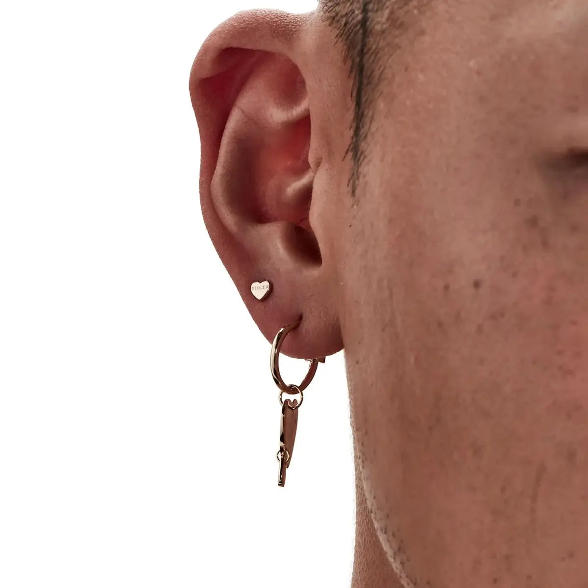 A close up of a model wearing Stolen Girlfriends Tiny Stolen Heart Earrings. Small, sweet and perfect for stacking.