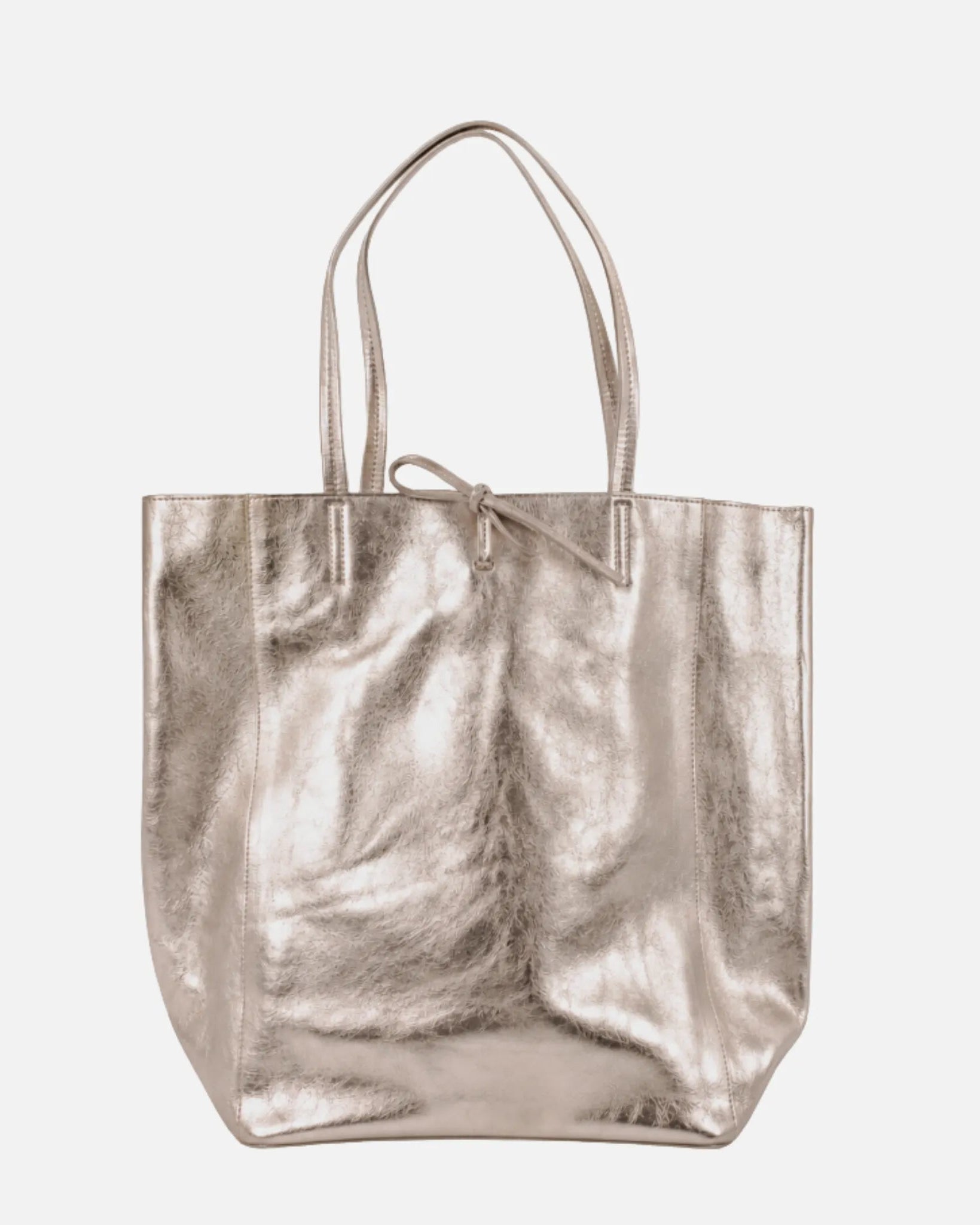 A metallic champagne-gold leather tote bag with dual top handles and a small bow detail at the top center, shown against a plain light gray background.