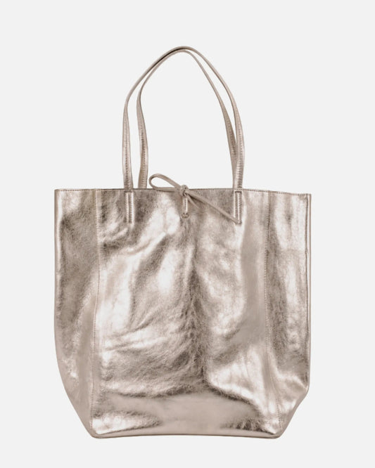 A metallic champagne-gold leather tote bag with dual top handles and a small bow detail at the top center, shown against a plain light gray background.