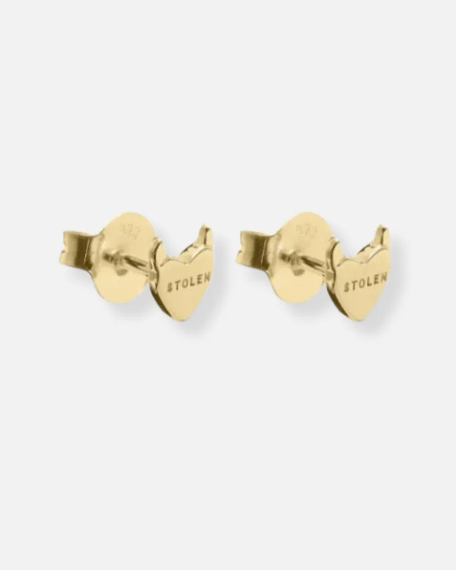 A pair of gold heart-shaped stud earrings with a butterfly back, featuring the brand name 'STOLEN' engraved on the side, set against a plain light gray background.