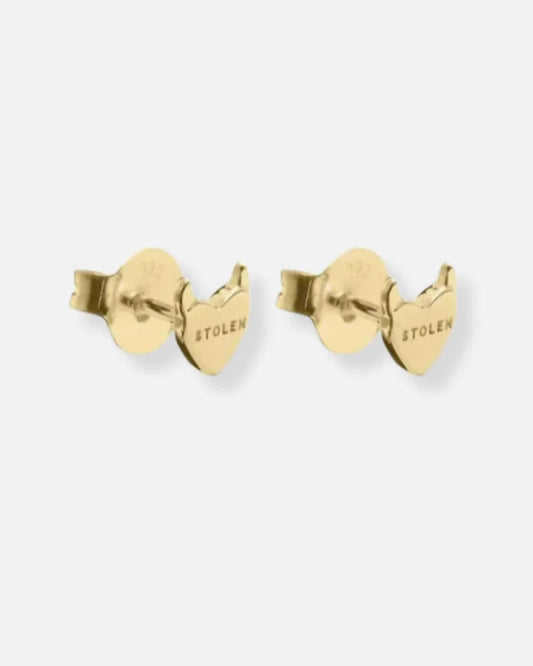 A pair of gold heart-shaped stud earrings with a butterfly back, featuring the brand name 'STOLEN' engraved on the side, set against a plain light gray background.