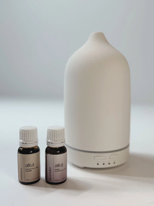Altasphere white essential oil diffuser and some essential oil bottles by its side