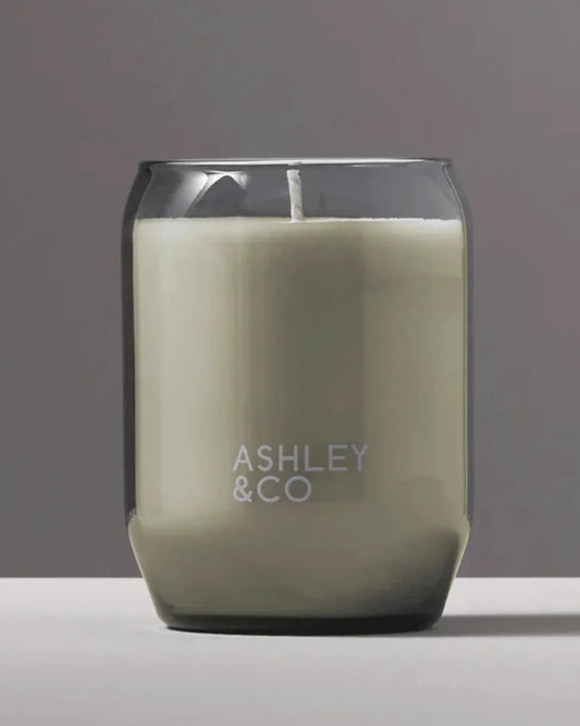 Ashley & Co Blossom & Gilt waxed perfume candle 310g in a smoky grey hand-blown glass vessel on a soft grey studio background
