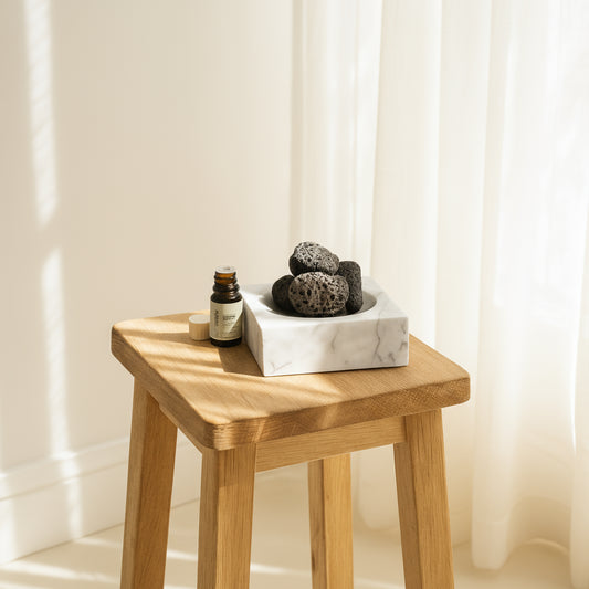 Small wooden table with the Marble Incense Holder with Lava Stones and a bottle of Alta essential oils. A very serene scene. 