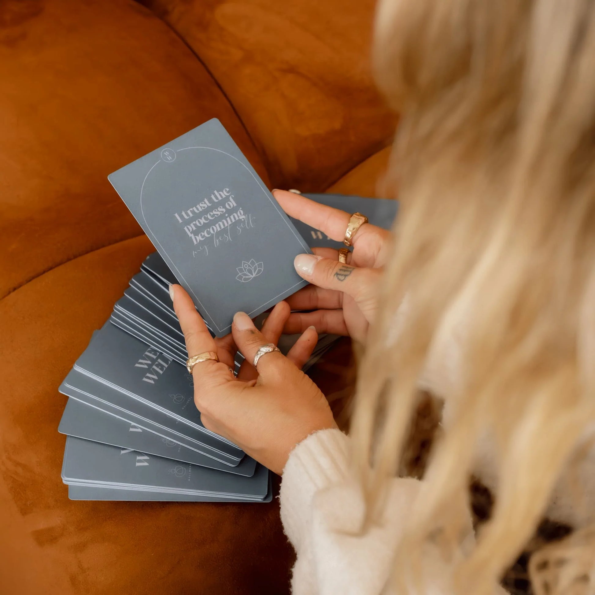 A person holding an Alta Weekly Wellbeing card that says "I trust the process of becoming".