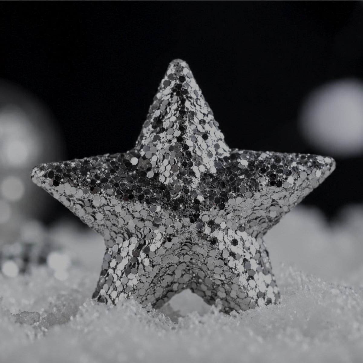 A silver glitter star resting in snow for Christmas