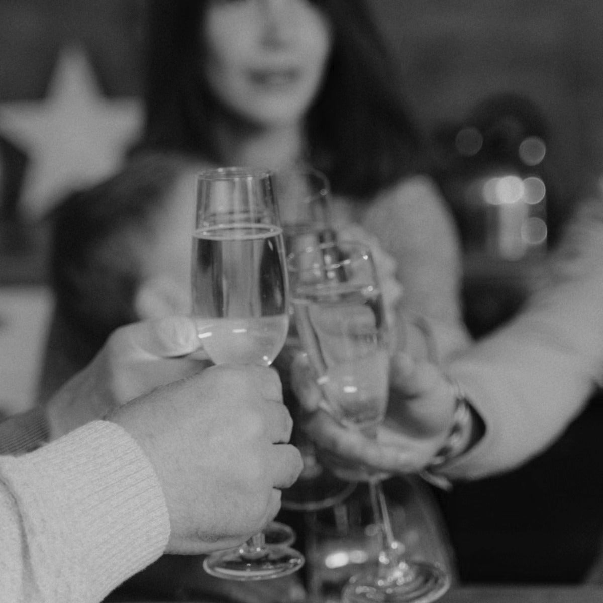 Friends toasting with champagne flutes at a housewarming, in black and white
